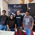 iFlair team members smiling at their Laracon India 2025 booth with the “Together We Grow” banner.